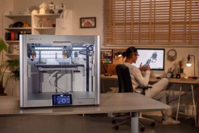 A 3D printer at work with a man in the background.