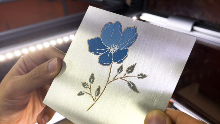 Metal laser engraving: A blue flower with green leaves is laser engraved on a steel plate.