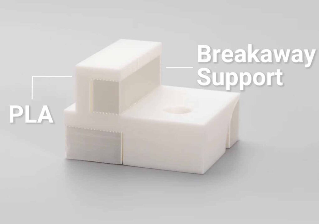 A white 3D-printed PLA object with two stacked blocks and a hollow center, featuring a gray breakaway support.